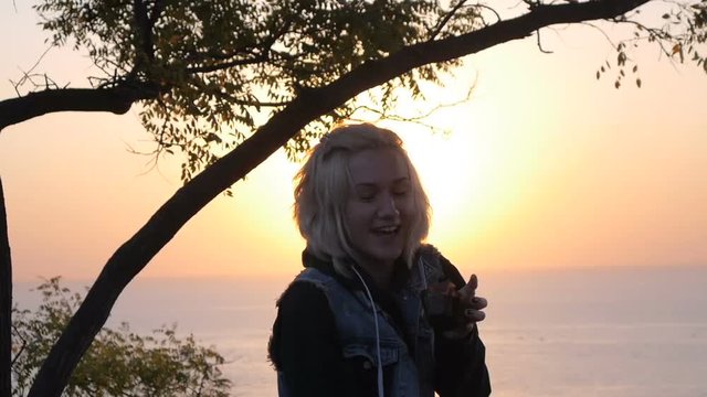 Smile girl with mobil phone enjoy moment when sunrise reflecting on the Sea