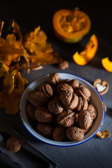 Walnuts in a bowl on a gray background and sliced pumpkin on the table