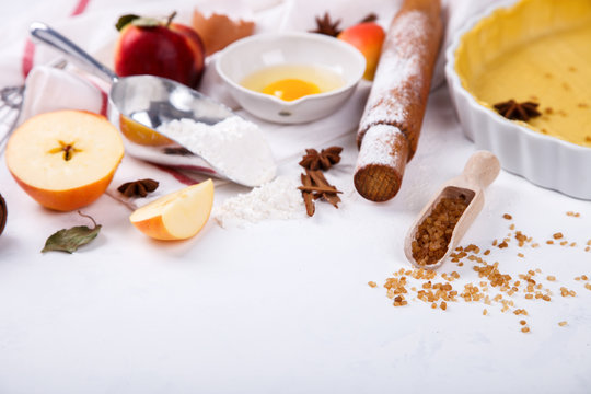 Baking Background. Ingredients  for baking Apple Pie  - apples,spices ,flour,  rolling pin, eggs, egg yolks, butter served, milk on white background.selective focus. Copy space.