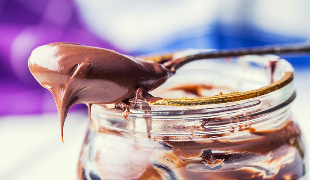 Chocolate spread in spoon. A jar of hazelnut chocolate spread.