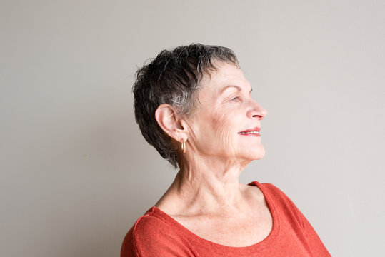 Older woman with short grey hair and orange top smiling with head back