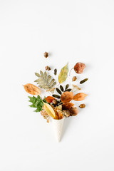 waffle cone with dried autumn leaves bouquet on white background, flat lay, top view