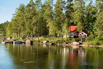Fototapeten Traditionelles, rotes Holzhaus an einem See in Småland, Schweden, an einem frühen Sommermorgen © Almgren