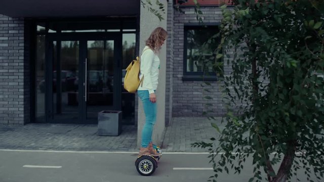 Girl riding on hoverboard. Girl runs along a modern building. Youth, fun, relaxed, take it easy. A popular means of transportation Hoverboard. A popular means of transportation Hoverboard.