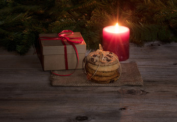 Neatly tied fresh cookies with warm glowing candle and gift 