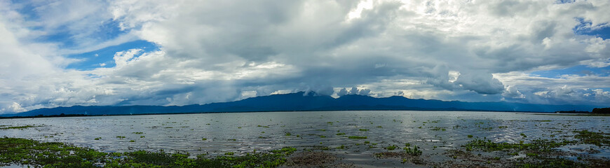 Panoramic beautiful view with the blue sky, white cloud and mountain of Kwan Phayao that is located in Phayao, Thailand. Many water hyacinth come with much plenty of water after several days raining.