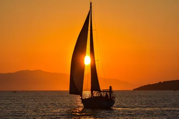 Afwasbaar Fotobehang Zeilen Zeilboot op de zee bij zonsondergang.