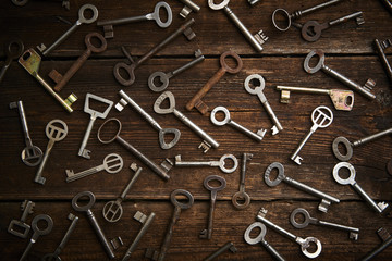 many different keys on brown wooden background.
