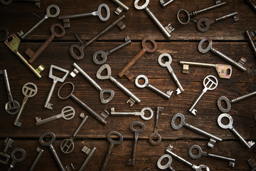 many different keys on brown wooden background.

