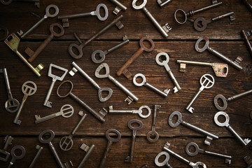 many different keys on brown wooden background.

