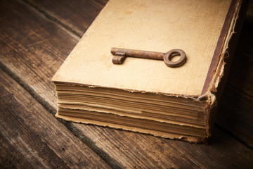 Obraz premium Vintage key over an old book on wooden background, Vintage color tone effected with copy space