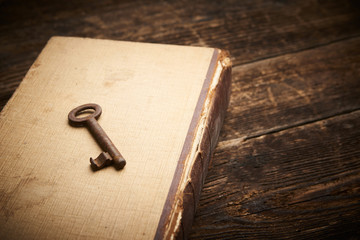 Vintage key over an old book on wooden background, Vintage color tone effected with copy space


