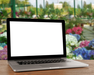 Laptop with blank screen on flower shop background