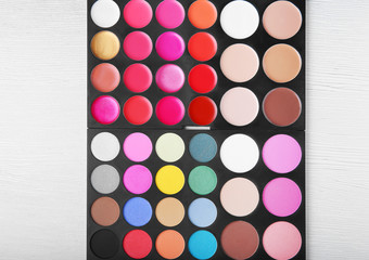 Colorful eye-shadow palette on wooden background
