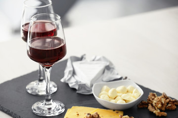 Glasses with red wine and tasty cheese on a board