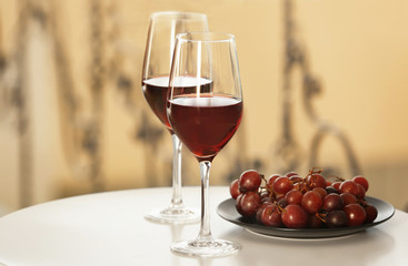 Glasses with red wine and grape on white table