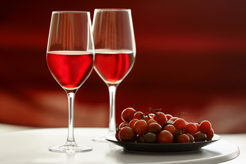 Glasses with red wine and grape on white table