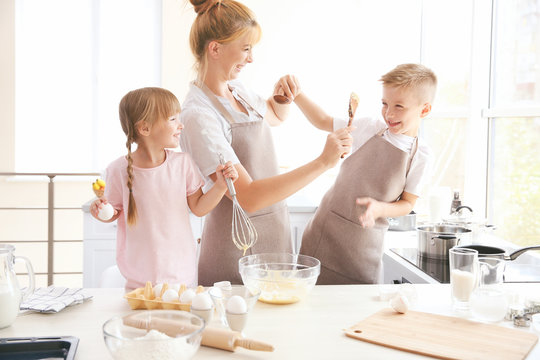 Mother and kids in kitchen making dough