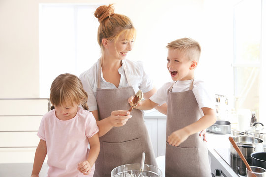 Mother and kids in kitchen making dough