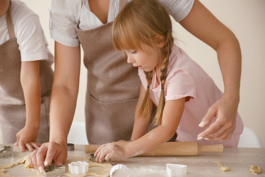 Young mother with kids making biscuits on table