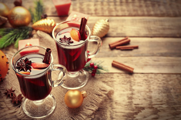Naklejka na ściany i meble Glass cups of delicious mulled wine with Christmas decor on sackcloth