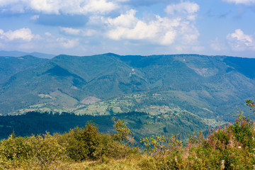 Top of the hill in Carpathian's. View to the village in mountains. Beautiful blue sky with clouds in the background. Summer time.