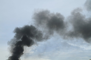 Black smoke from fire burning on the sky