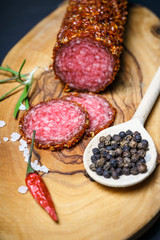dried salami crusted in ground red pepper on dark background