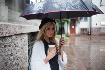 Cheerful woman in the street drinking morning coffee