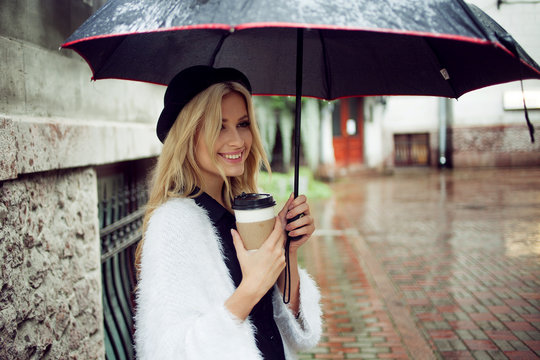 Cheerful woman in the street drinking morning coffee