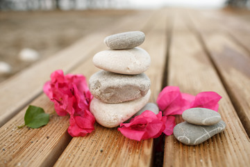 Fototapeta na wymiar Zen stones spa at sandy beach with tropical pink flowers