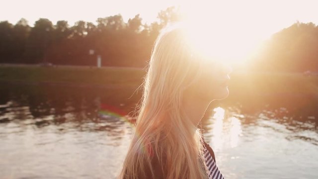 Young girl posing on the gren grass near the river at sunset