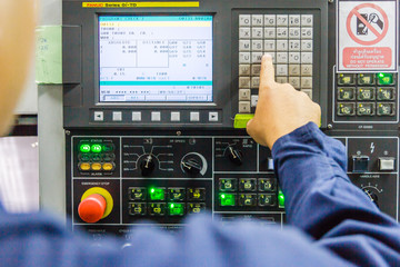 mechanical technician working with Control Panel of CNC machine center at tool workshop