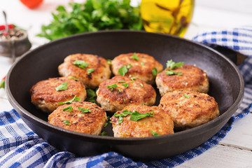 Juicy delicious meat cutlets in pan on a wooden table.