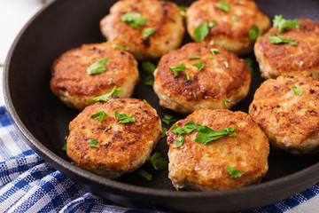 Juicy delicious meat cutlets in pan on a wooden table.