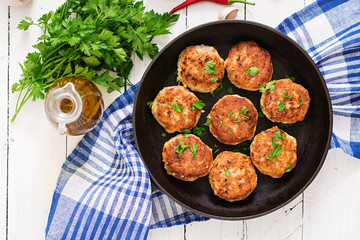 Juicy delicious meat cutlets in pan on a wooden table. Top view