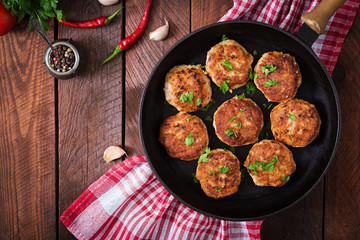 Juicy delicious meat cutlets in pan on a wooden table. Top view