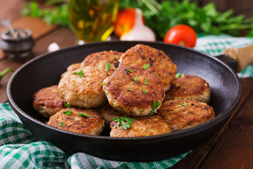 Juicy delicious meat cutlets in pan on a wooden table.