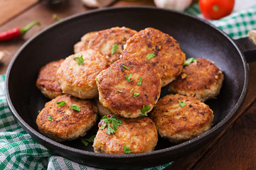 Juicy delicious meat cutlets in pan on a wooden table.
