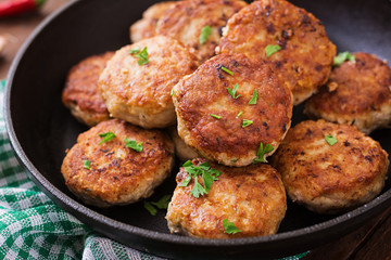 Juicy delicious meat cutlets in pan on a wooden table.