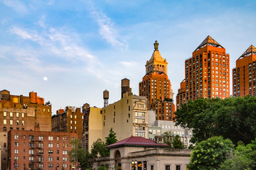 Old buildings around Union Square Park in New York City with the moon rising in the sky