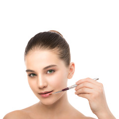 Portrait of beautiful young brunette woman with clean face. Beauty spa model girl with perfect fresh clean skin applying cosmetic brush. Youth and skin care concept. Isolated on a white background.