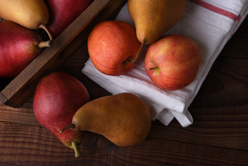 Fresh picked pears and apples in a wood crate and towel on a rustic wood table. Top view in horizontal format.