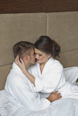 happy woman looking at husband while lying in bed 