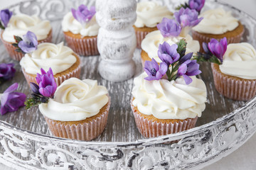 cupcakes with purple edible flowers on vintage cake stand for te