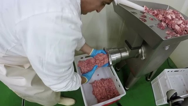 Butcher Mincing Meat with Mincer Machine