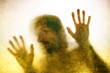 Trapped man, back lit silhouette of hands behind matte glass
