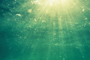 Underwater shot with sunrays and bubbles in deep tropical sea