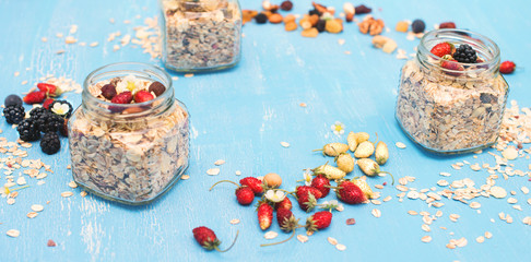 Jars with muesli, berries, nuts and seeds on blue rustic background