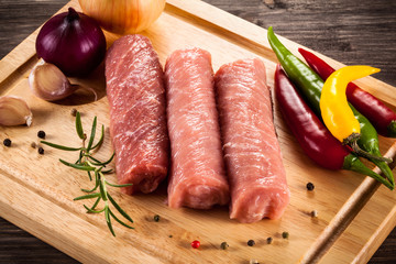 Raw pork chops on cutting board and vegetables 